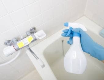 風呂場で防カビ剤を持つ手