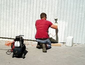 スプレーガンで壁を塗装する男性