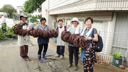 サツマイモのつるで作ったリースを持つ女性たち
