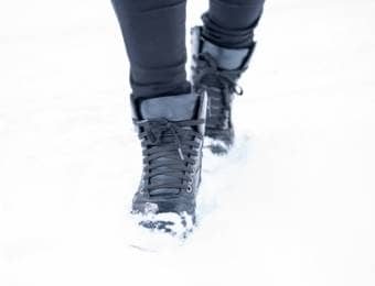 防寒長靴で雪道を歩く人